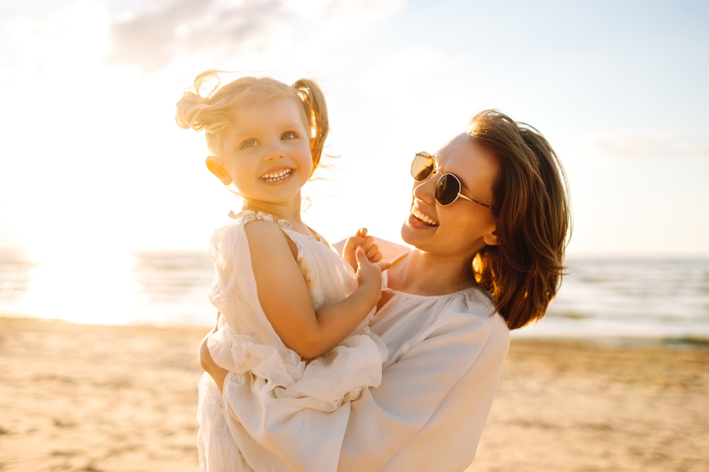 Smiling mother holding her young daughter at the beach